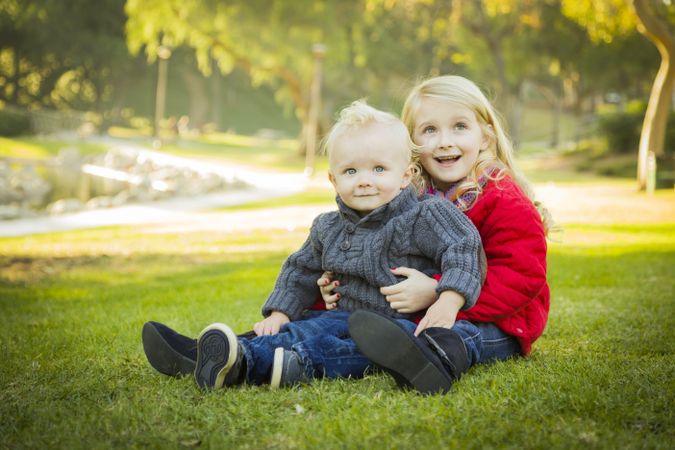 Little Girl with Baby Brother Wearing Coats at the Park.