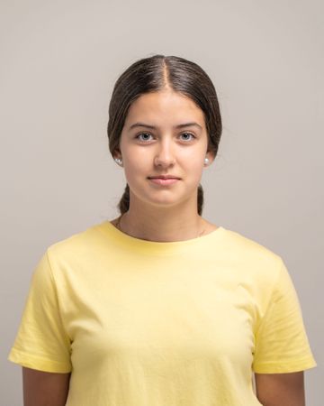 Headshot portrait of a beautiful young woman with a neutral expression looking at the camera.