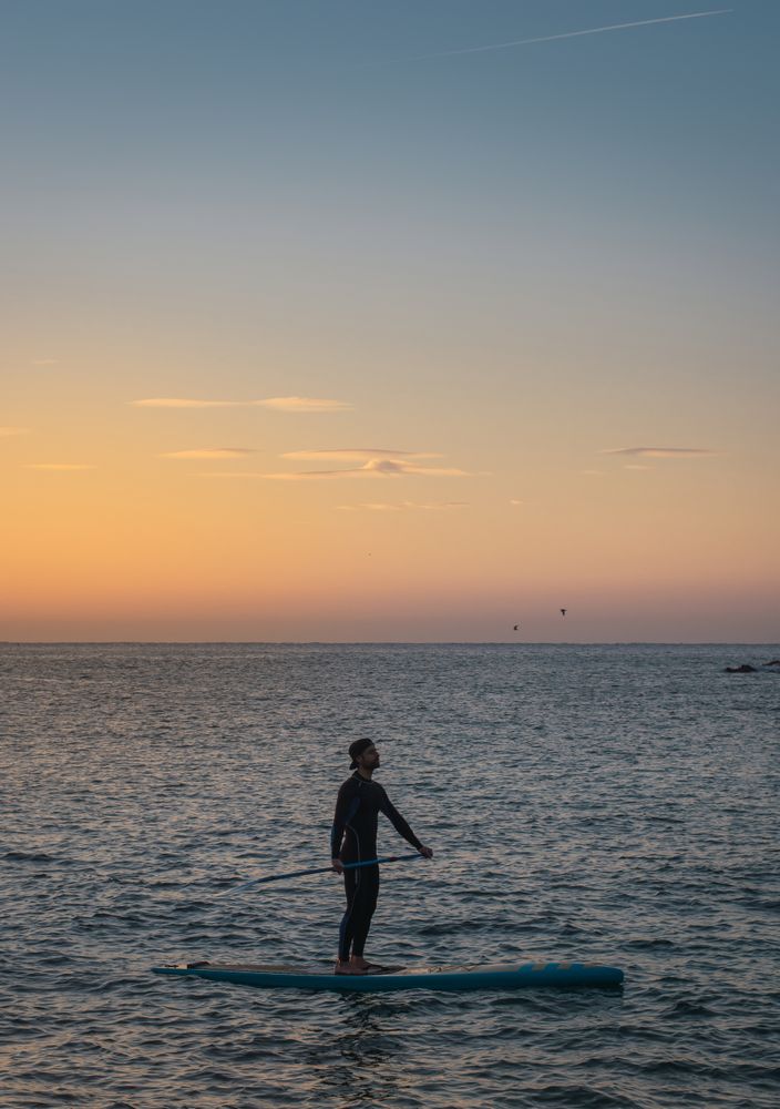 Man practicing paddle surfing with neoprene in a sunrise