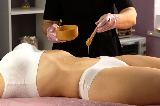 Warm honey applied in circular motion during abdomen therapy session.