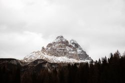 Big mountains near pine forest on cloudy weather