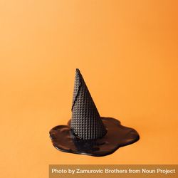 Witch hat made of ice cream cone with melted ice cream on orange background 4OWvv4
