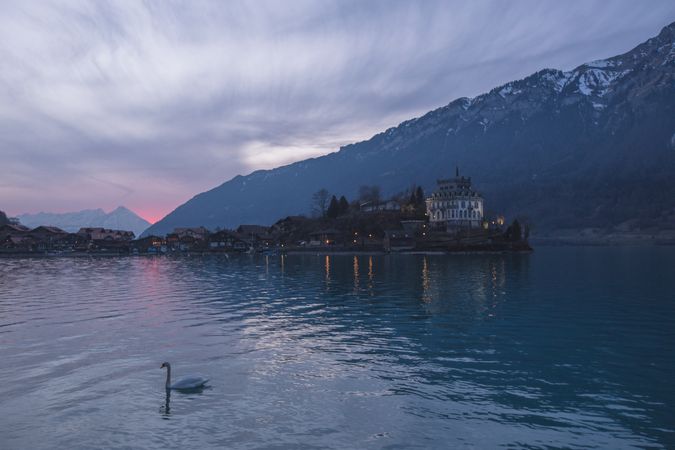 Tranquil lake with boats on pier against mountains and houses