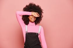 Young Black woman covering eyes with arm