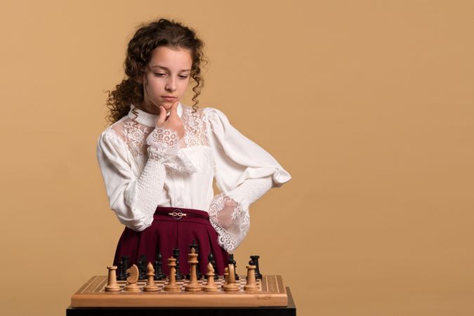 Young girl thinking deeply about chess move.