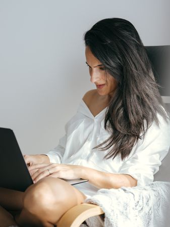 female freelancer typing on netbook sitting on chair
