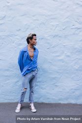 Asian male standing in front of wall in blue shirt and jeans, vertical 0V1Zvb