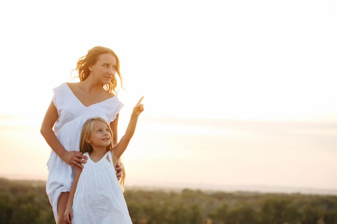 Little girl pointing out something to her mother outside at dusk