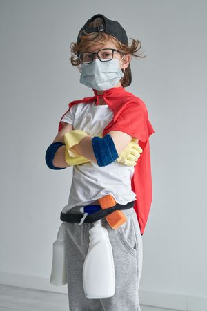 Little cleaner in superhero costume at home