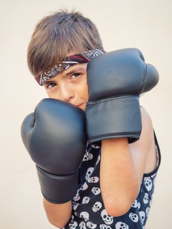 Sporty boy in boxing gloves beating punch bag