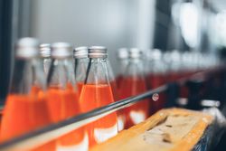 Orange colored soda bottles on conveyor belt in factory