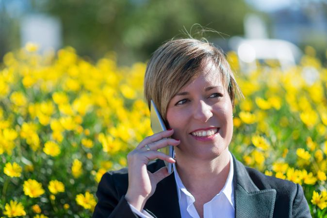Professional woman talking on phone in front of yellow flowers