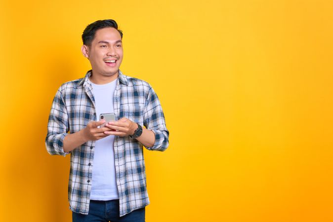 Happy Asian male with his phone in studio shoot with copy space