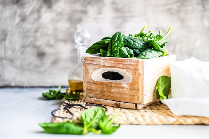 Box of spinach leaves on rattan placemat with copy space