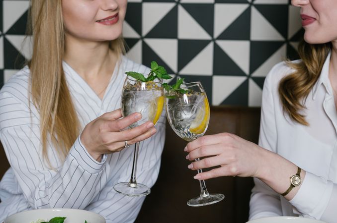 Cheerful friends clinking glasses in cafe