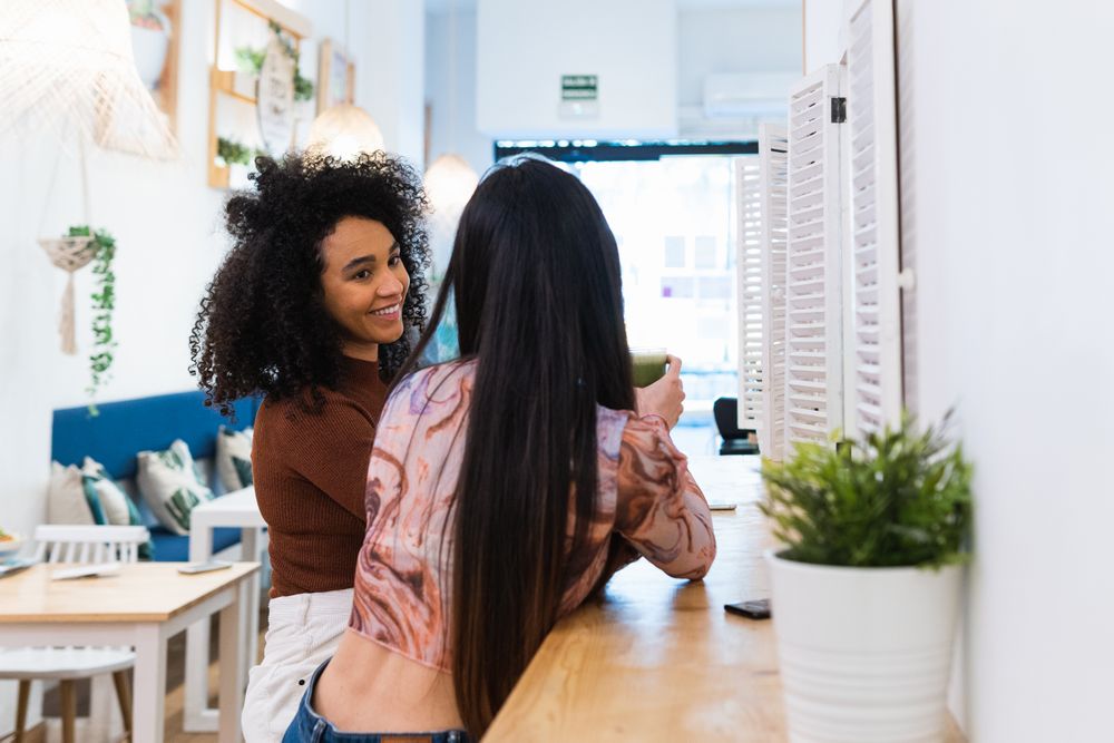 Cheerful women drinking smoothie in bar
