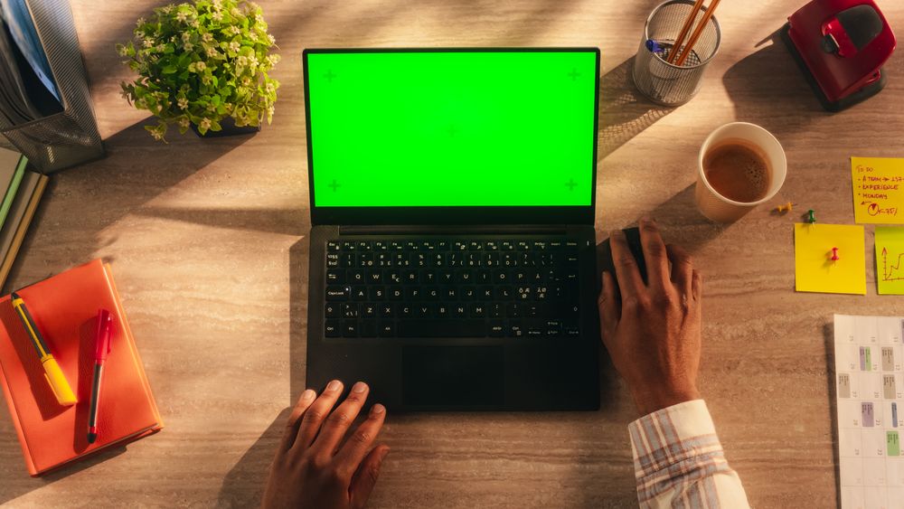 Anonymous African Manager Typing on a Laptop with Mock-Up Green Screen Chromakey Display. Businessman Using Computer, Working on Corporate Partnership Project Plan. Top Down View