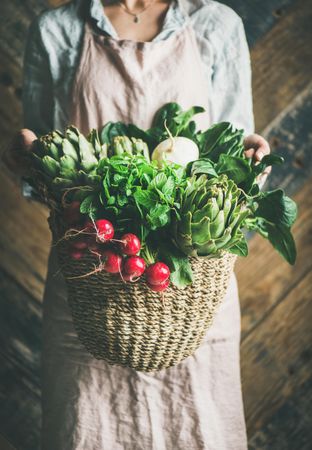 Woman holding basket of fresh picked garden produce