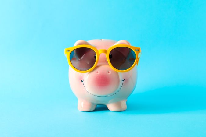 Happy piggy bank with sunglasses on color background, space for text. Finance, saving money