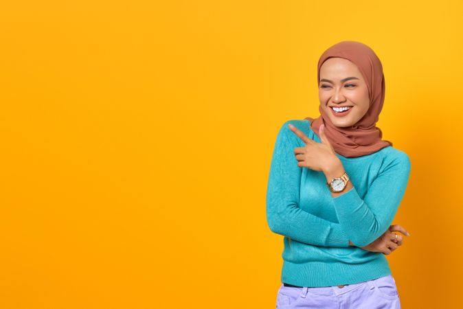 Excited Muslim woman with her finger pointing to the side