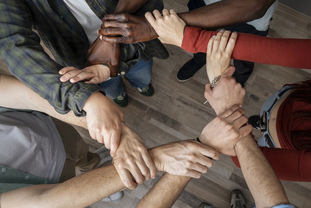 Diverse hands joined together in circle symbolizing unity, teamwork, and collaboration