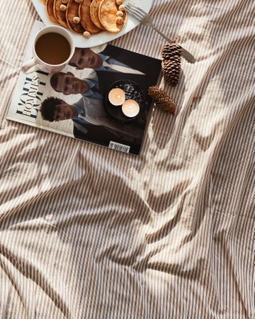 Mini pancakes and coffee on a duvet with magazine
