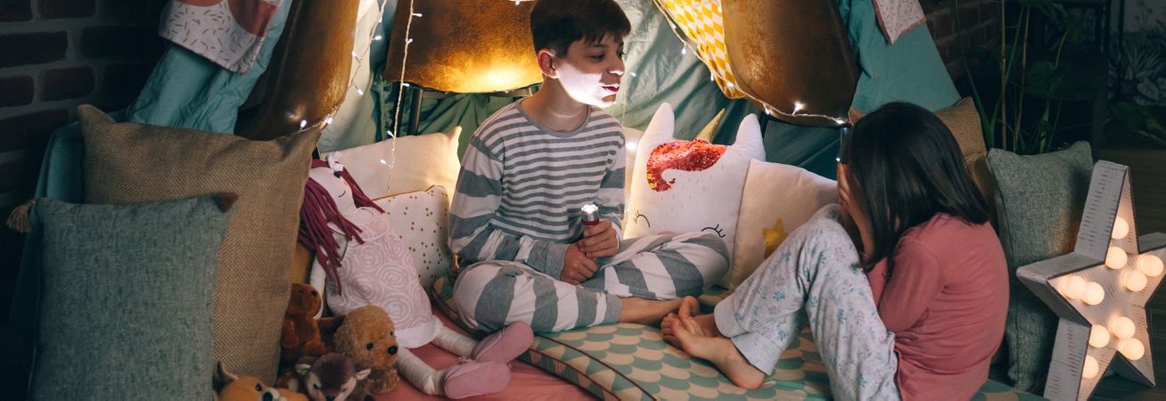 Banner of kid making terror gesture illuminated with lantern while scared girl cover face with hands