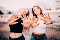 Two young women holding their hands in the foreground showing traces of gold glitter