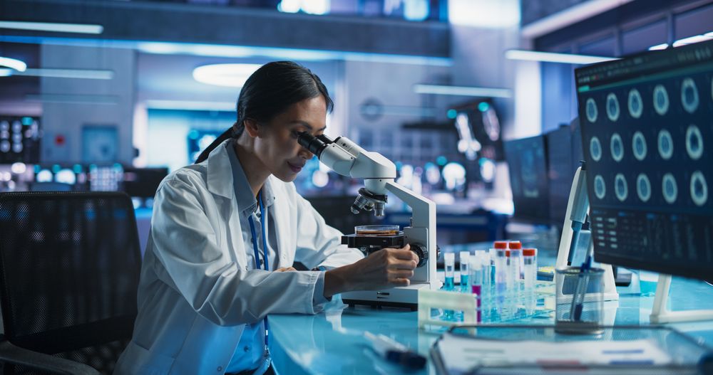 Medicine Development Laboratory: Asian Female Scientist Using Microscope, Analyzes Petri Dish Sample.