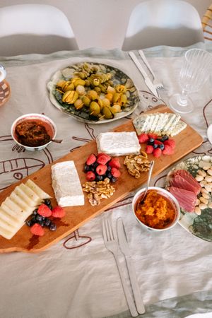 Cheese plate with berries and walnuts on table with olives and cured meats