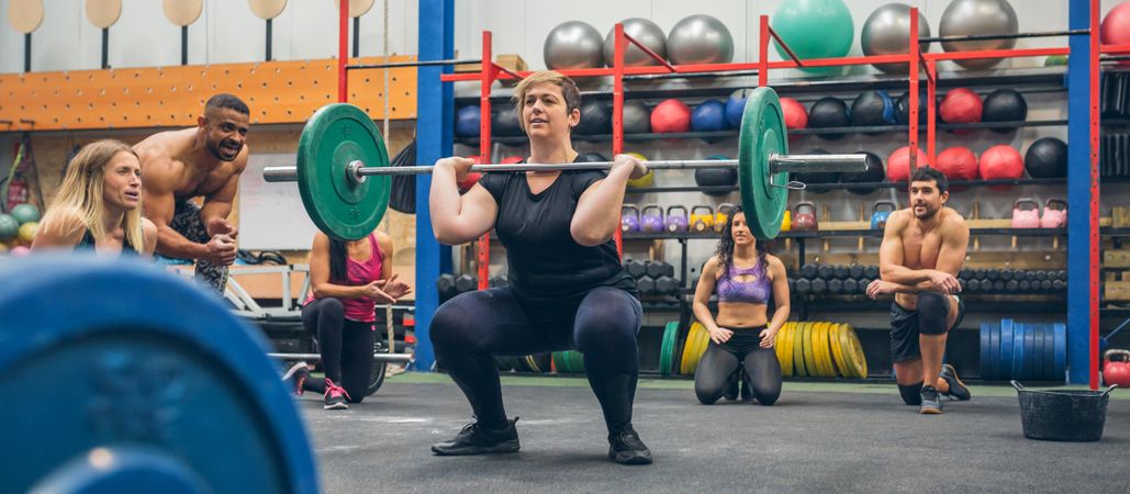 Woman weightlifting while her gym mates cheering her on