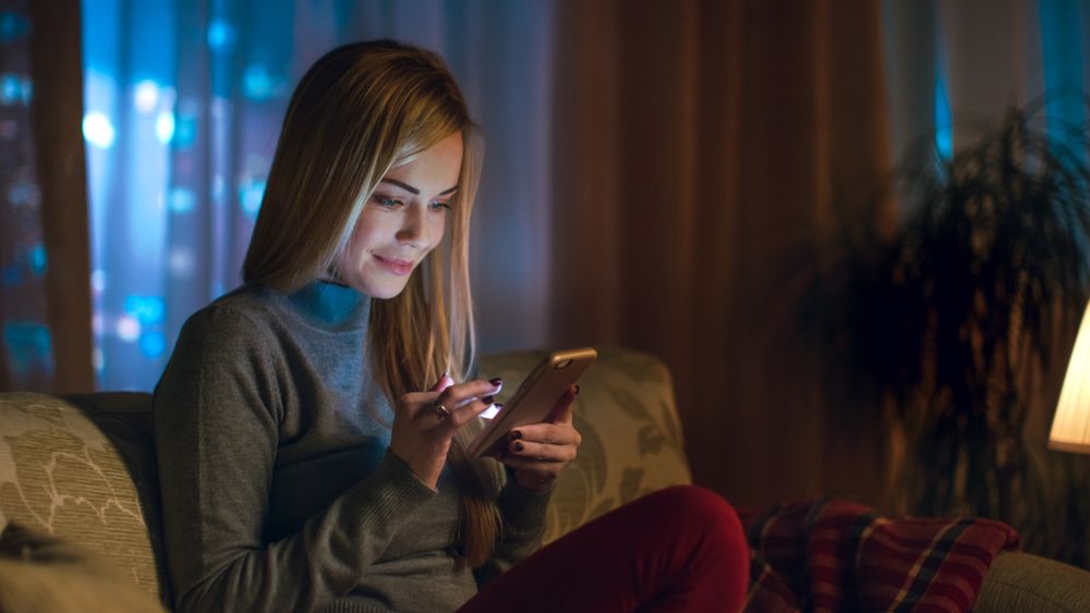Young Woman Uses Smartphone with Interest.