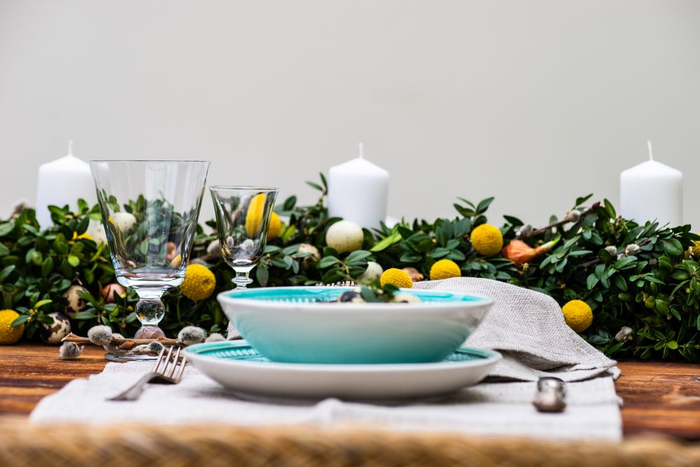 Side view of Easter table setting with decorative eggs in foliage