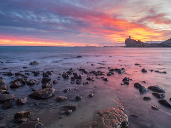 Sundown sky over sea and stony coast