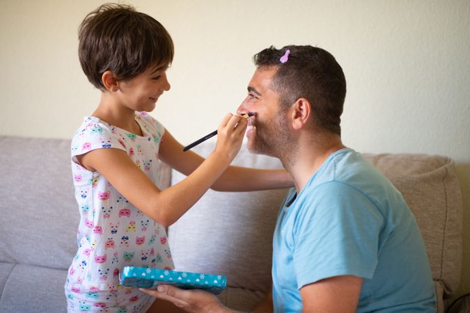 Young girl practicing make up on her dad