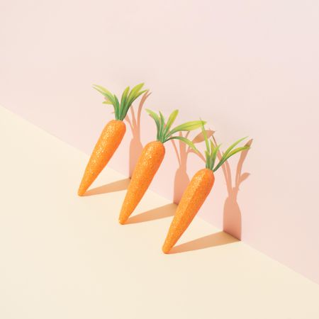 Row of carrots on pastel yellow background