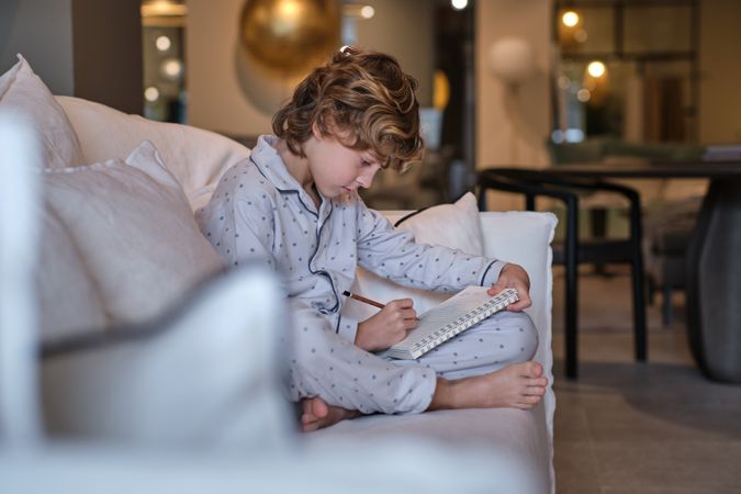 Boy in pajama drawing in sketchbook at home