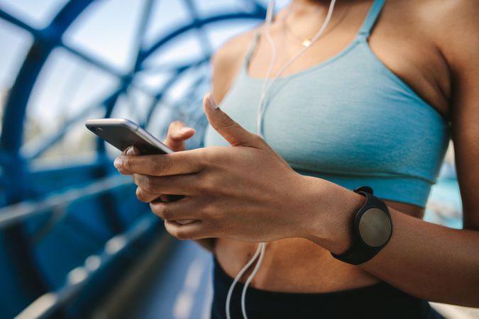Fit woman wearing sports bra and holding cell phone