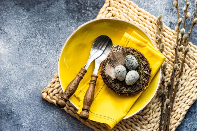 Top view of Easter holiday table setting with yellow plate and bird's nest
