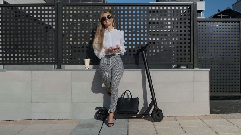 Businesswoman with mobile and her scooter next
