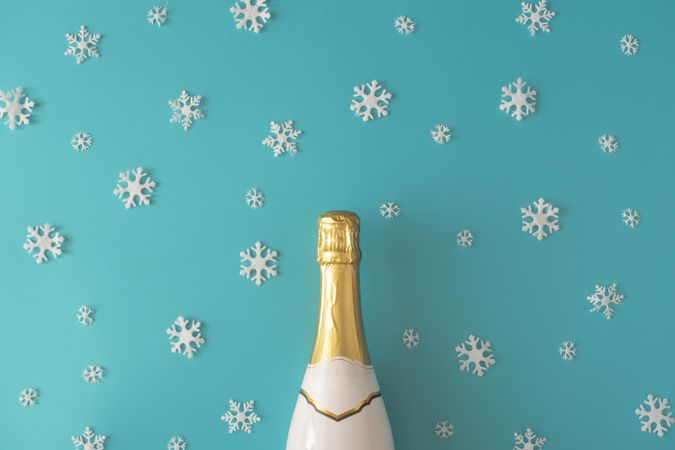 Bottle of sparkling wine on blue background with snowflakes