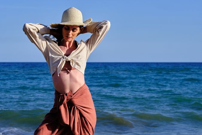 A fashion model with a hat at the beach before sunset