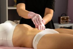 Therapist performing abdominal massage during honey body treatment.