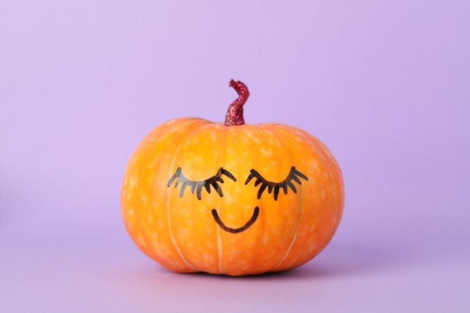 Pumpkin with smile on violet background, space for text