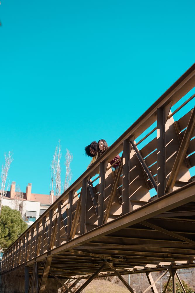 Two women talking on a bridge.
