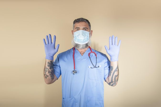 Portrait of doctor gesturing while standing against wall background