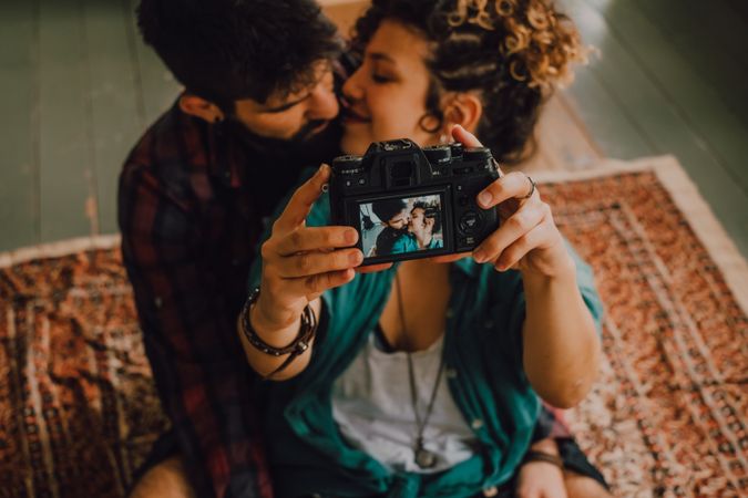 Joyful couple embracing and taking selfie on camera at home