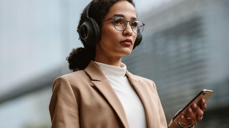 Confident female executive listening to music on cell phone