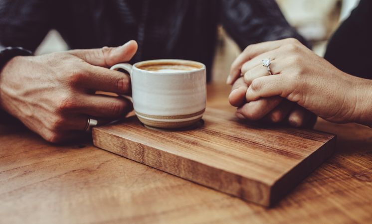 Man holding hand of his wife while having coffee at a cafe