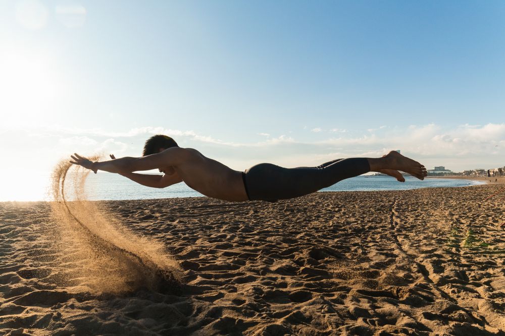Sporty man levitating over sand during workout